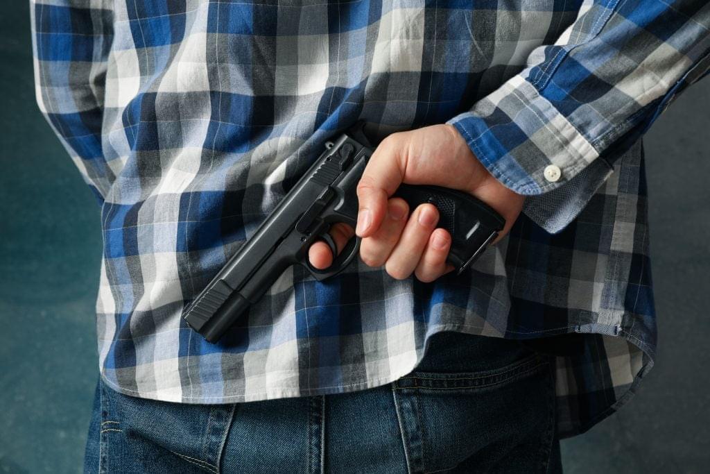 A man hold a gun from behind. Self defense weapon